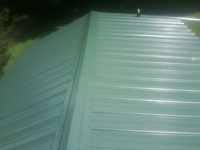 New green metal panels meeting at the ridge of a roof — Flat Roof Repair work by our crew in Morse Bluff