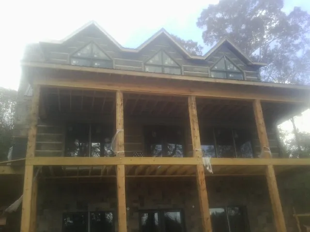 Dormers and porch framing on a large log home under construction — Roof Coating work by our crew in Morse Bluff