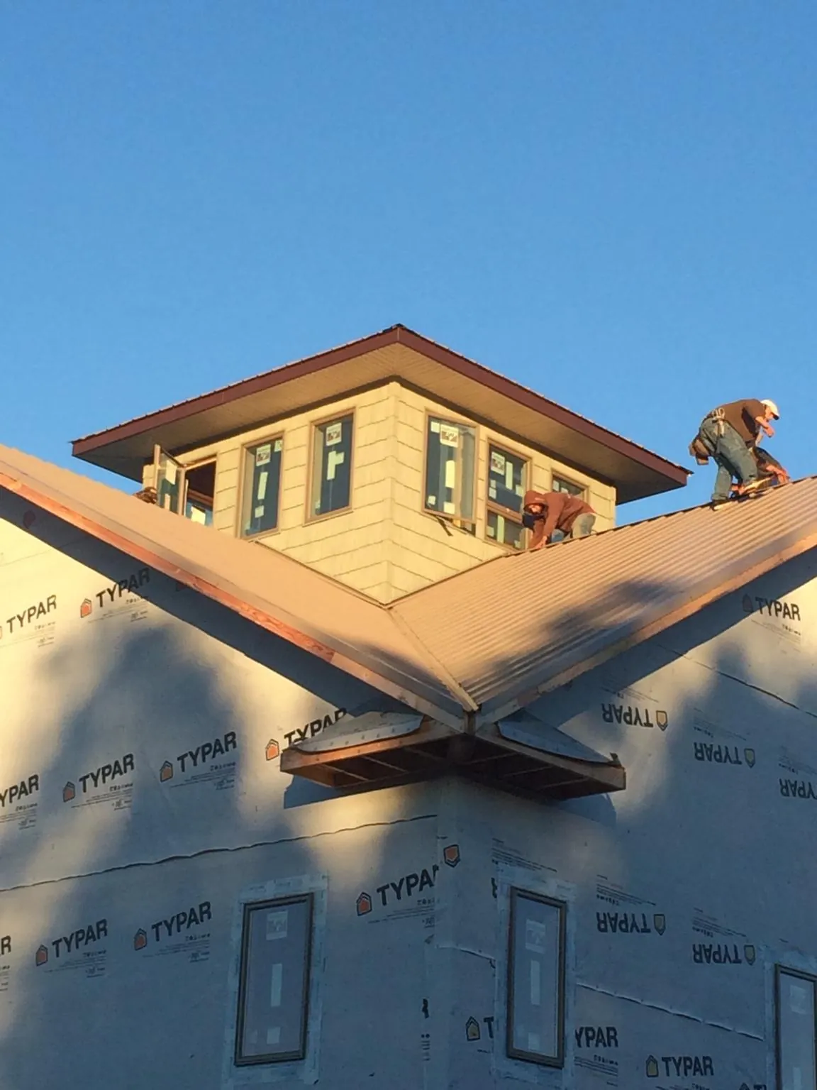 Roofers working around a rooftop cupola on a new metal roof at sunset — Roof Waterproofing in Morse Bluff by Roofing Brothers